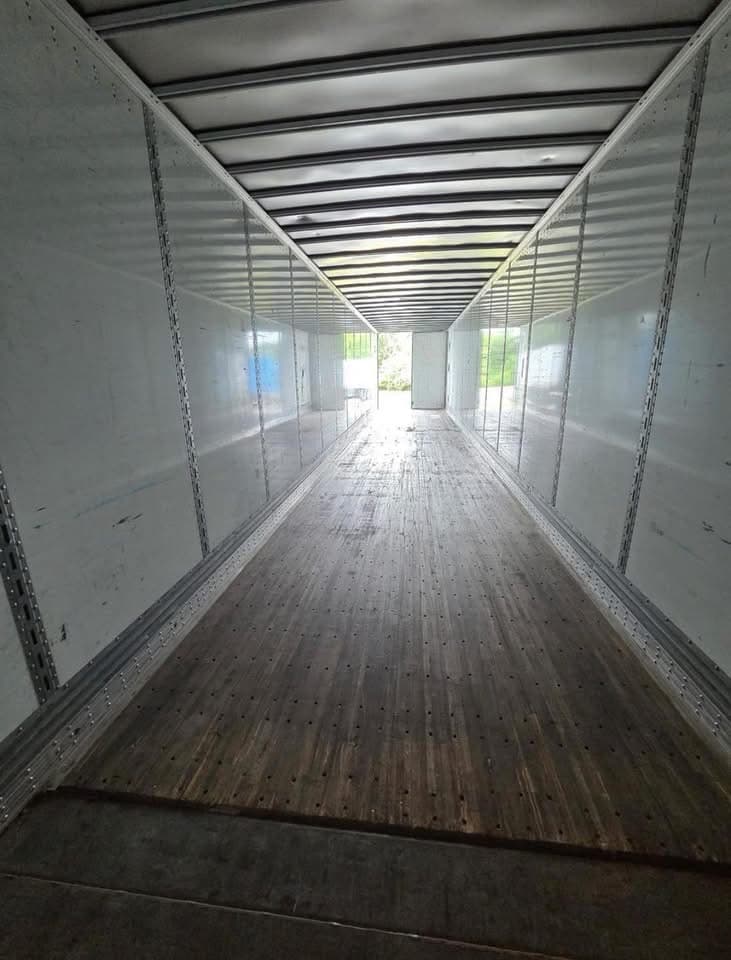 Interior de un furgón seco de 53 pies mirando hacia las puertas traseras, con rieles logísticos E-track y piso de madera dura